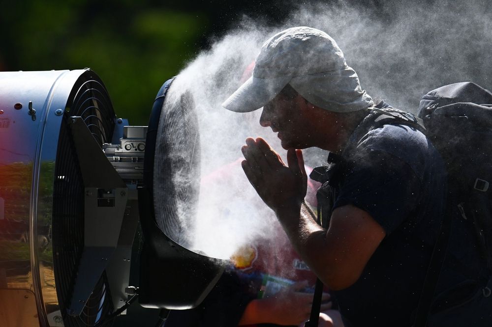Spectateur se rafraîchissant avec un ventilateur lors d'une chaude journée d'été 2026